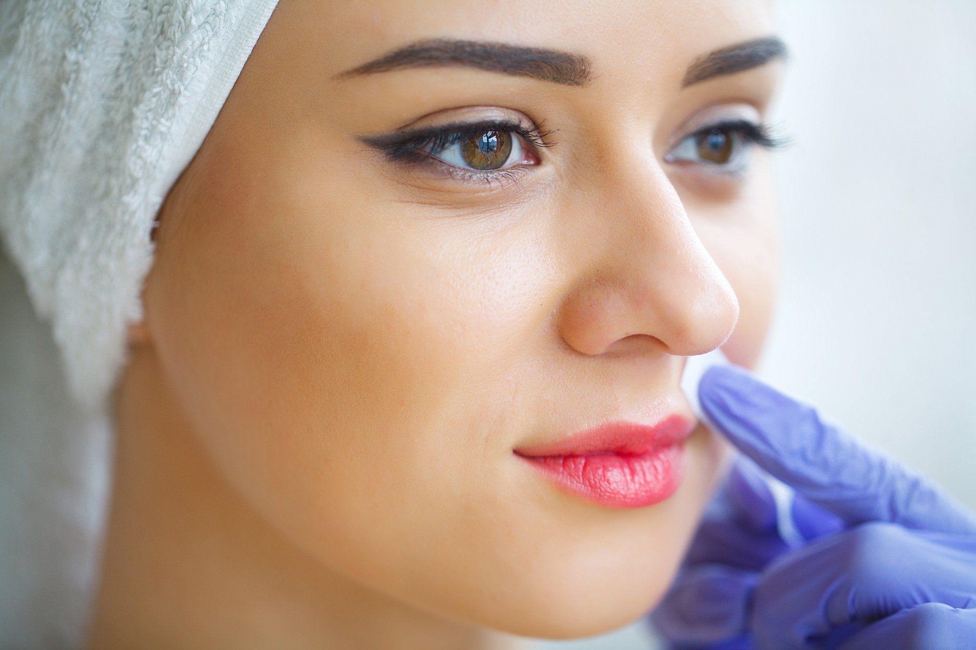 Beautician waxing young woman's eyebrows in spa center