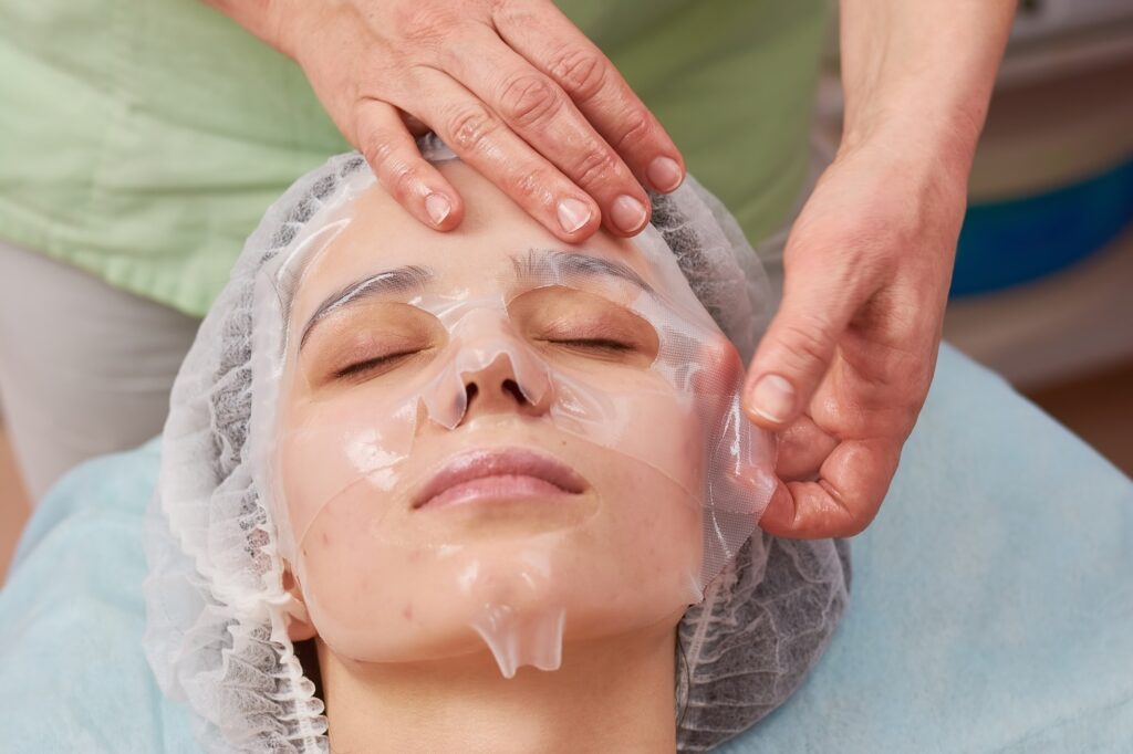 Hands applying collagen facial mask